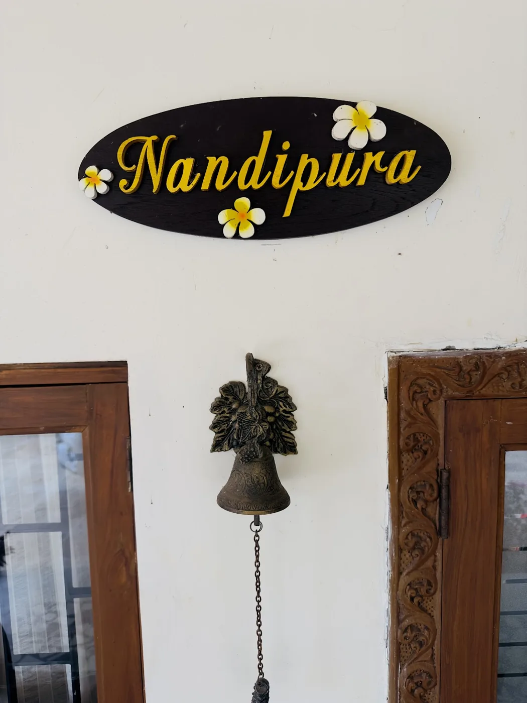 The hand-painted Nandipura nameplate above the bungalow door, with a brass bell beside it