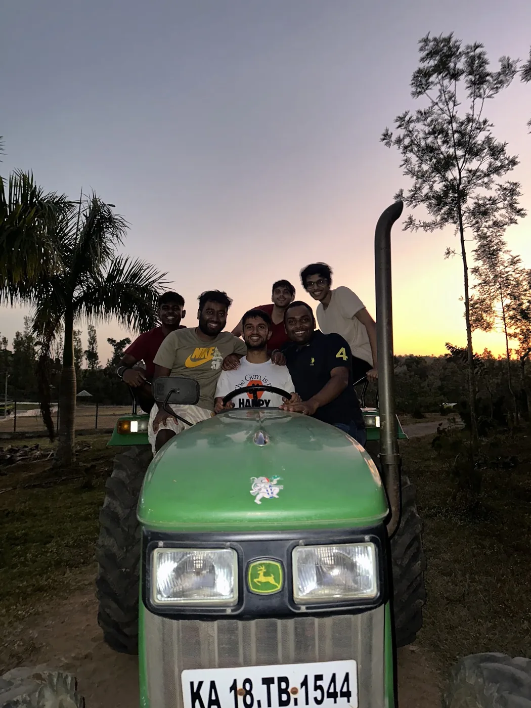 A group of friends riding out across the estate on a tractor at sunset